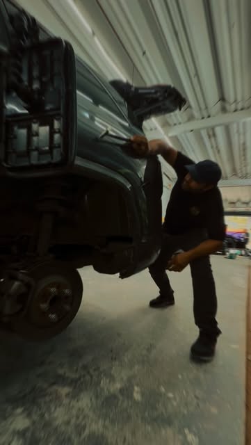 Profissional trabalhando na lateral de um veículo elevado